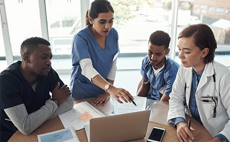 A group of doctors and nurses collaborate at a conference table
