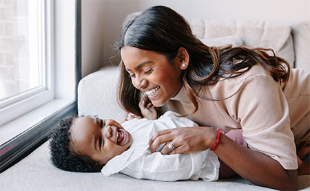 An adult tickling a baby making them laugh.